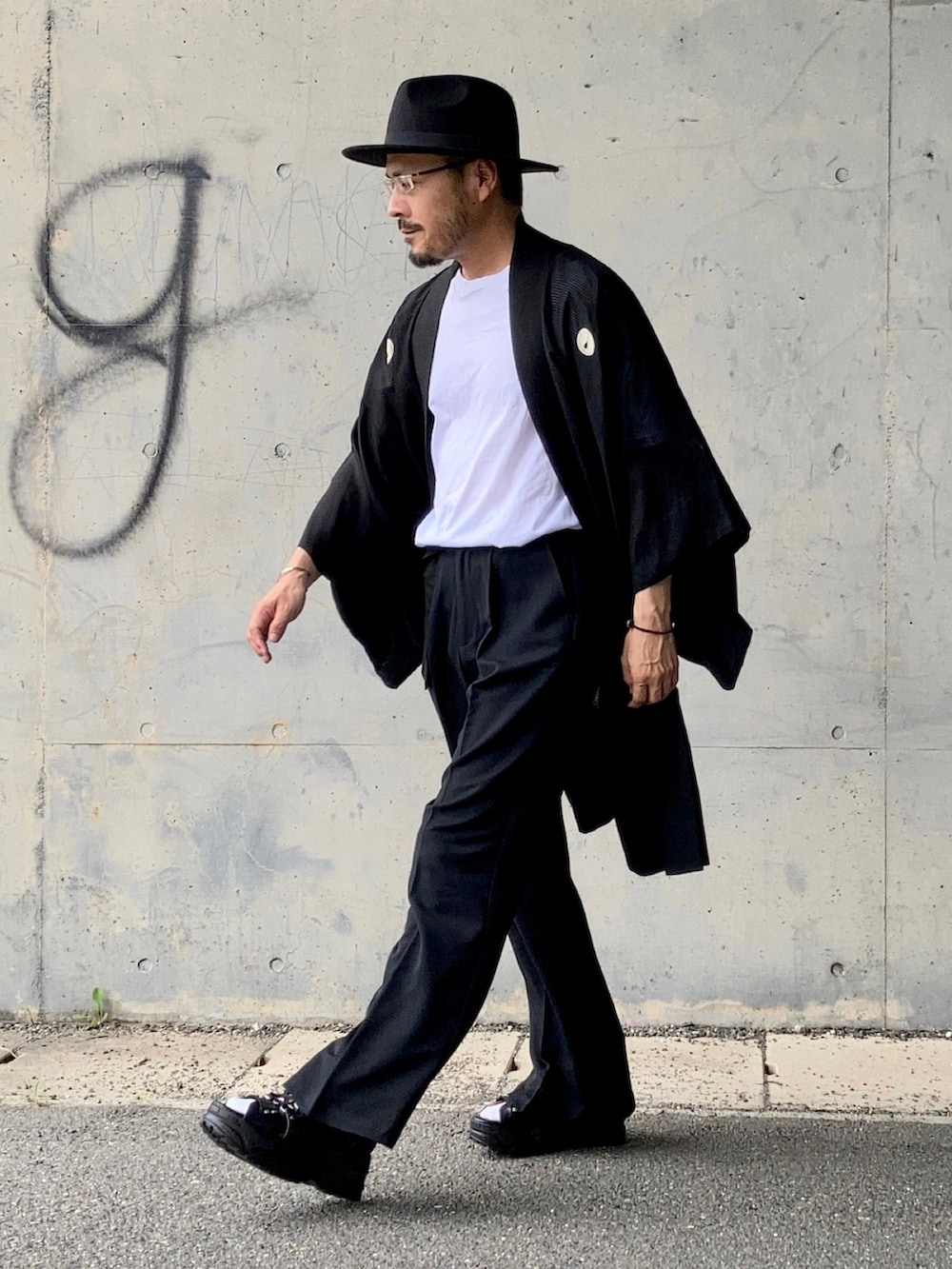 ホワイト系のTシャツ/カットソー、ブラック系のスラックス、ブラック系のサンダルを着用したメンズの夏コーディネートの4枚目の写真