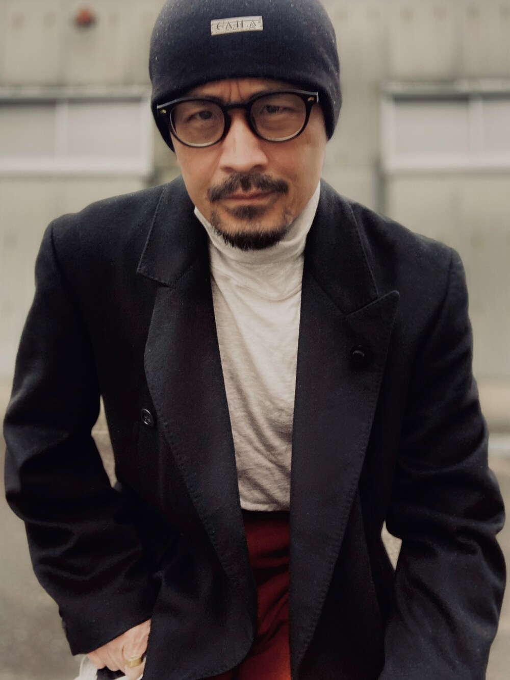 グレー系のTシャツ/カットソー、ブラック系のチェスターコート、オレンジ系のカーゴパンツを着用したメンズの冬コーディネートの5枚目の写真