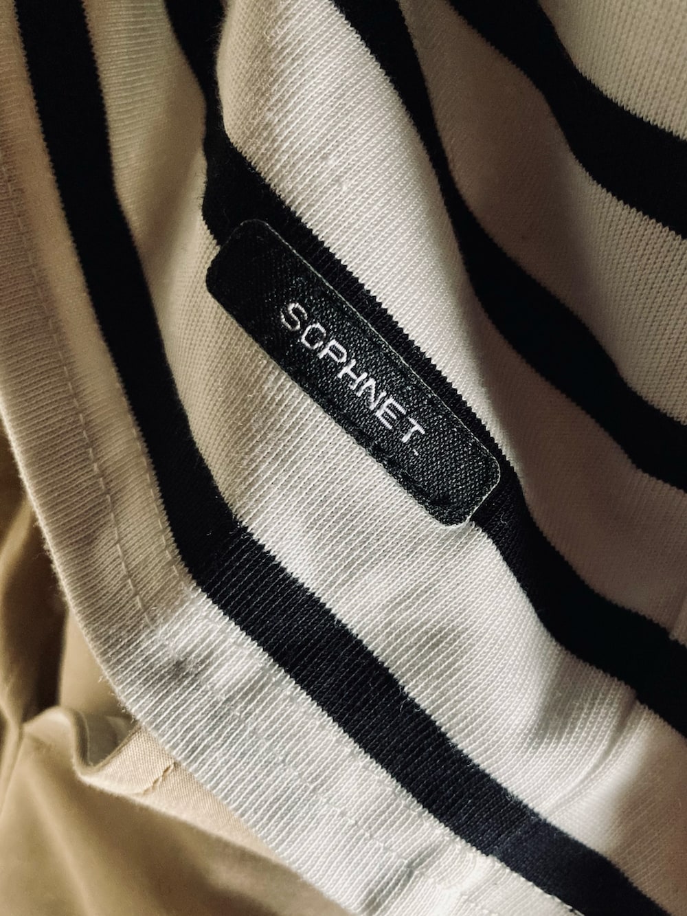 ブラック系のTシャツ/カットソー、ベージュ系のチノパンツ、ブラック系のスニーカーを着用したメンズの春コーディネートの3枚目の写真