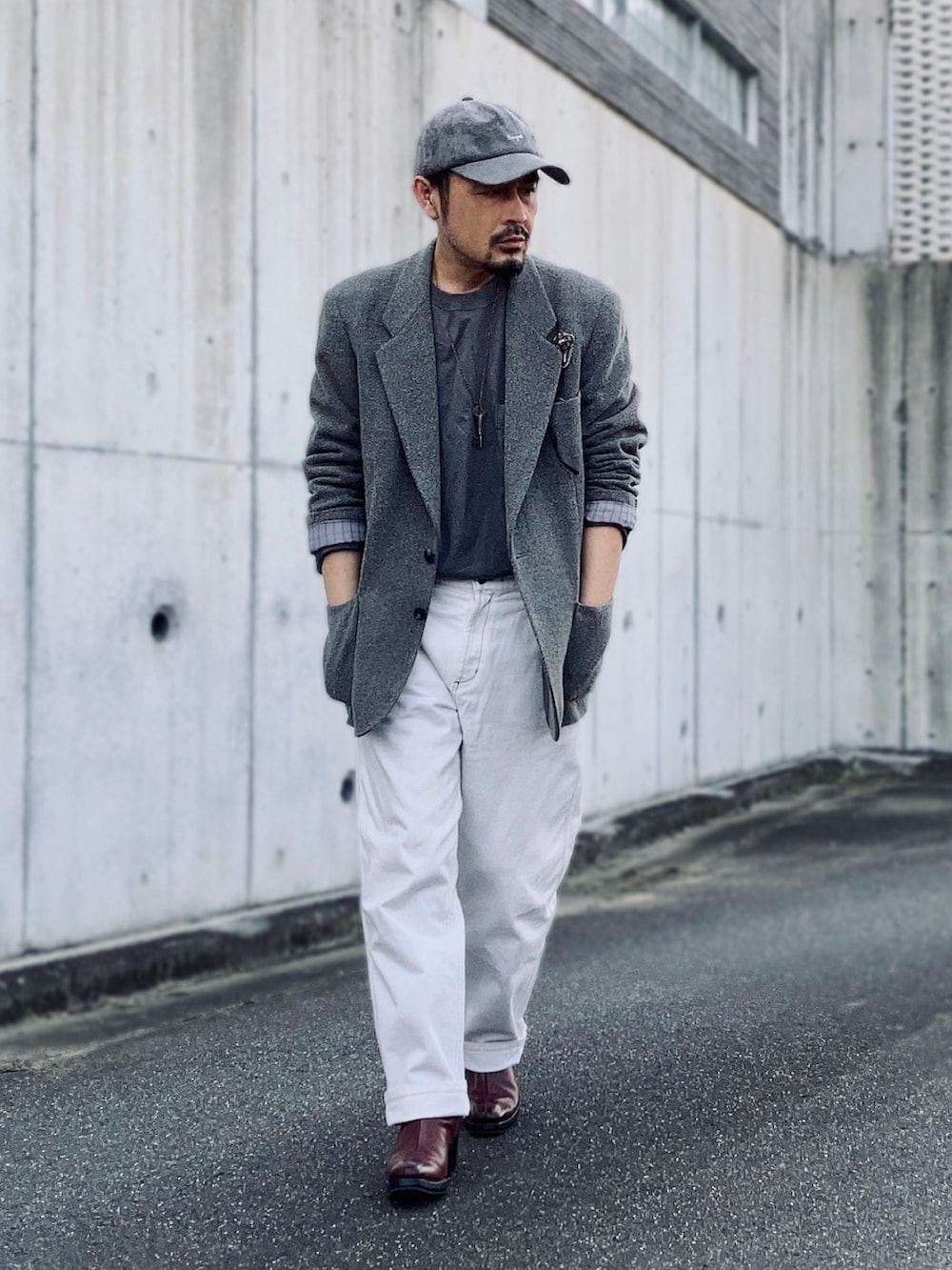 グレー系のテーラードジャケット、グリーン系のニット/セーター、ホワイト系のデニムパンツを着用したメンズの春コーディネートの3枚目の写真