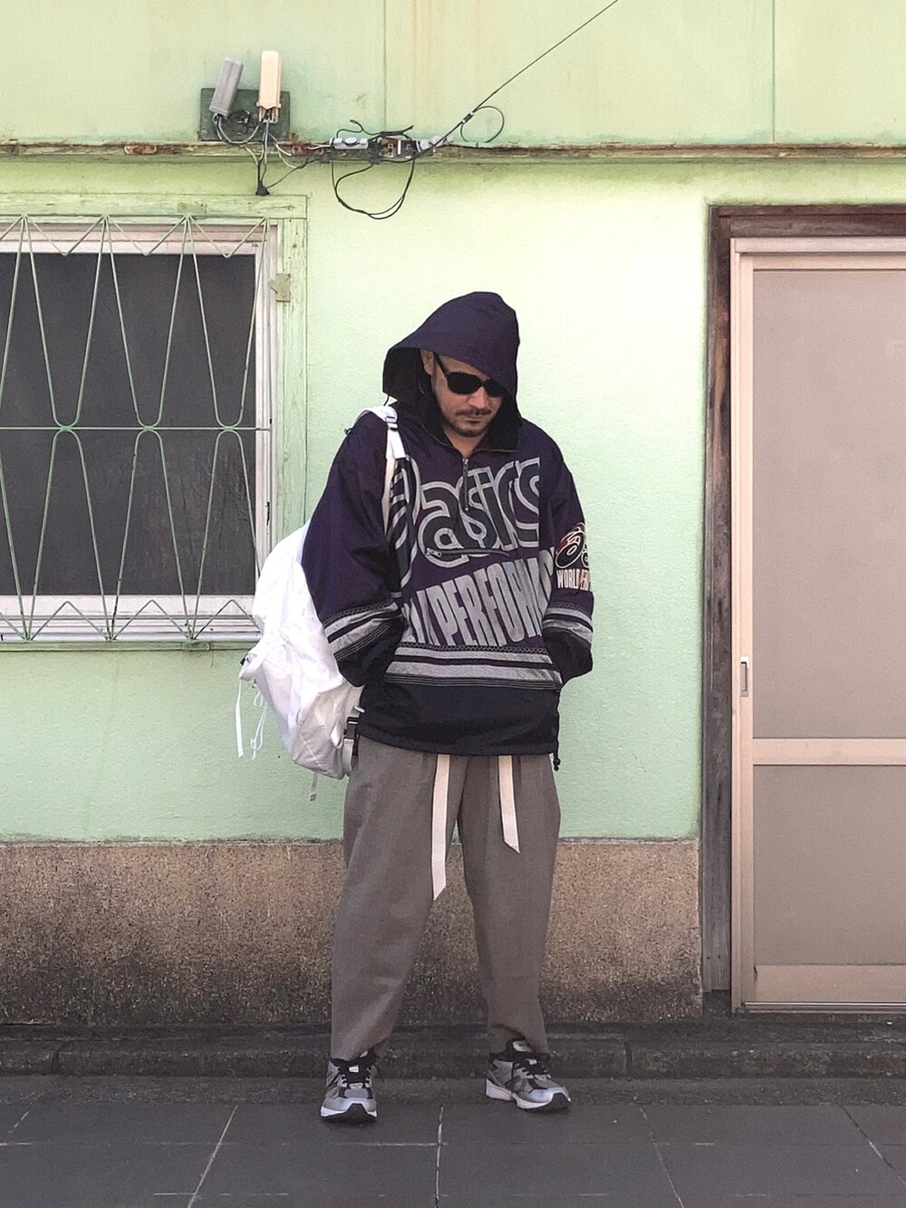 パープル系のナイロンジャケット、ブラウン系のスラックス、ブラック系のスニーカーを着用したメンズの秋コーディネートの3枚目の写真