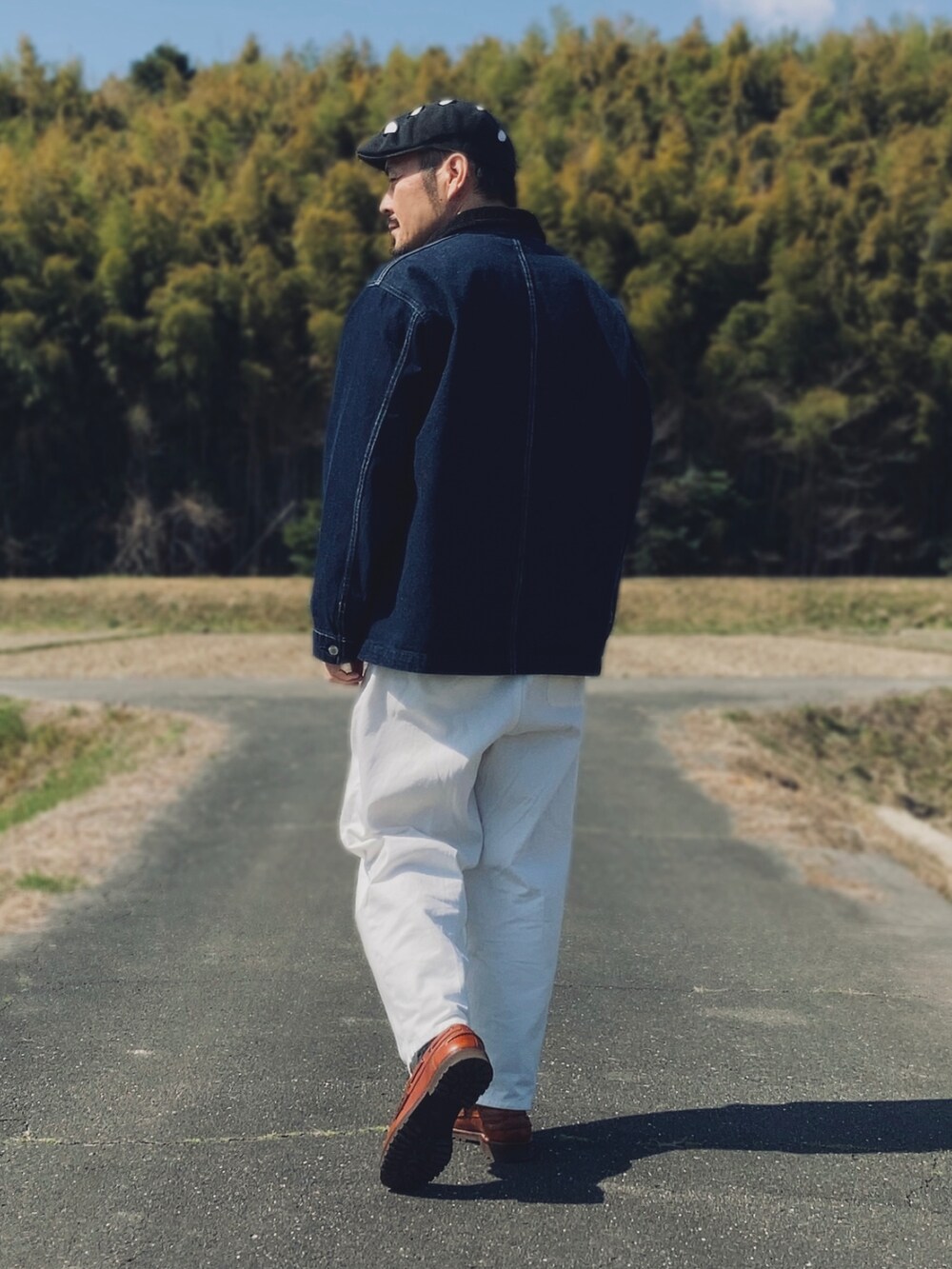 ブラウン系のTシャツ/カットソー、ブルー系のデニムジャケット、ホワイト系のスラックスを着用したメンズの春コーディネートの4枚目の写真