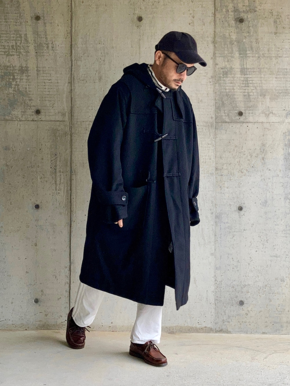 ブラック系のTシャツ/カットソー、ブラック系のダッフルコート、ホワイト系のデニムパンツを着用したメンズの秋コーディネートの5枚目の写真