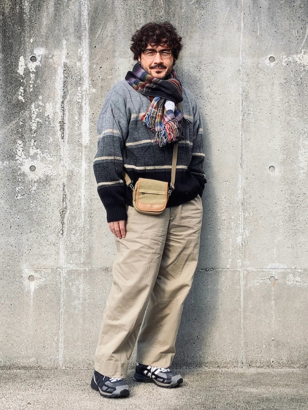 グレー系のニット/セーター、ベージュ系のチノパンツ、ブラック系のスニーカーを着用したメンズの冬コーディネートの2枚目の写真