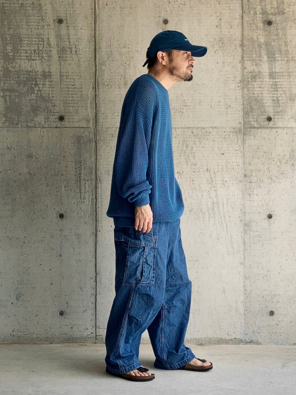 ブルー系のニット/セーター、ブルー系のカーゴパンツ、ブラック系のサンダルを着用したメンズの秋コーディネートの2枚目の写真