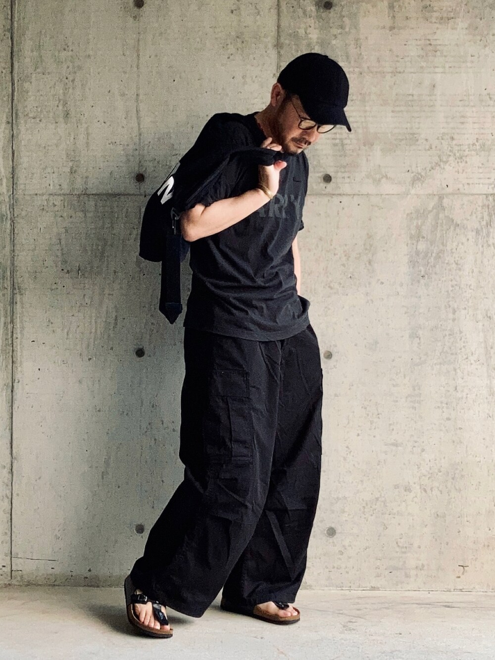 ブラック系のTシャツ/カットソー、ブラック系のカーゴパンツ、ブラック系のサンダルを着用したメンズの夏コーディネートの4枚目の写真