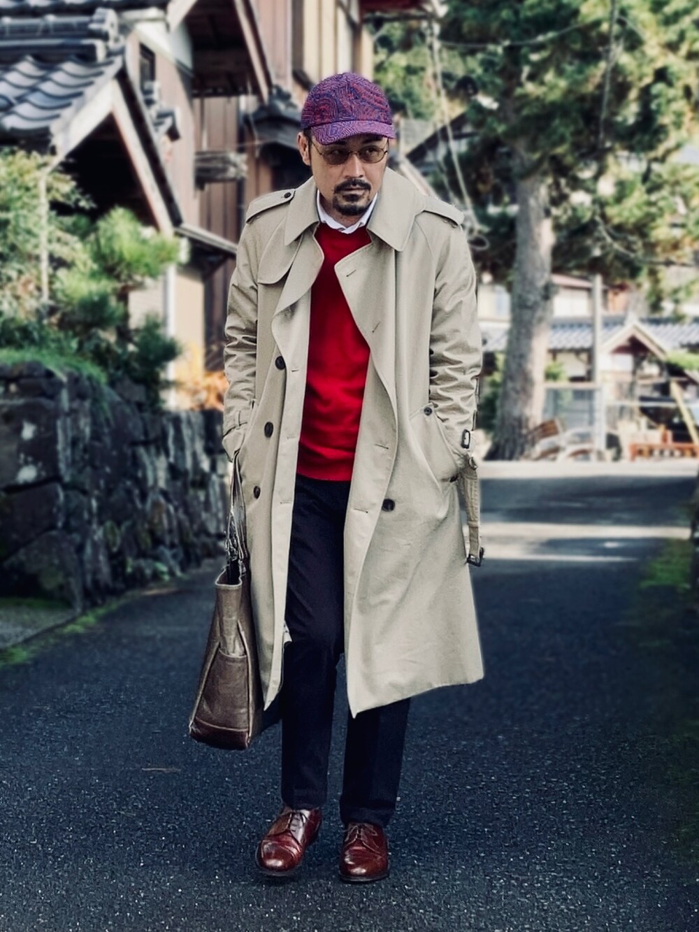 レッド系のニット/セーター、ホワイト系のシャツ/ブラウス、ベージュ系のトレンチコートを着用したメンズの秋コーディネートの4枚目の写真