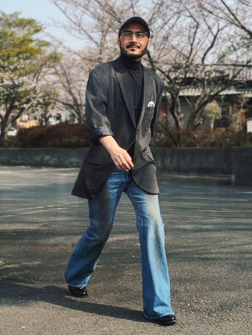 グレー系のテーラードジャケット、ブルー系のデニムパンツ、ブラック系のブーツを着用したメンズの春コーディネートの2枚目の写真