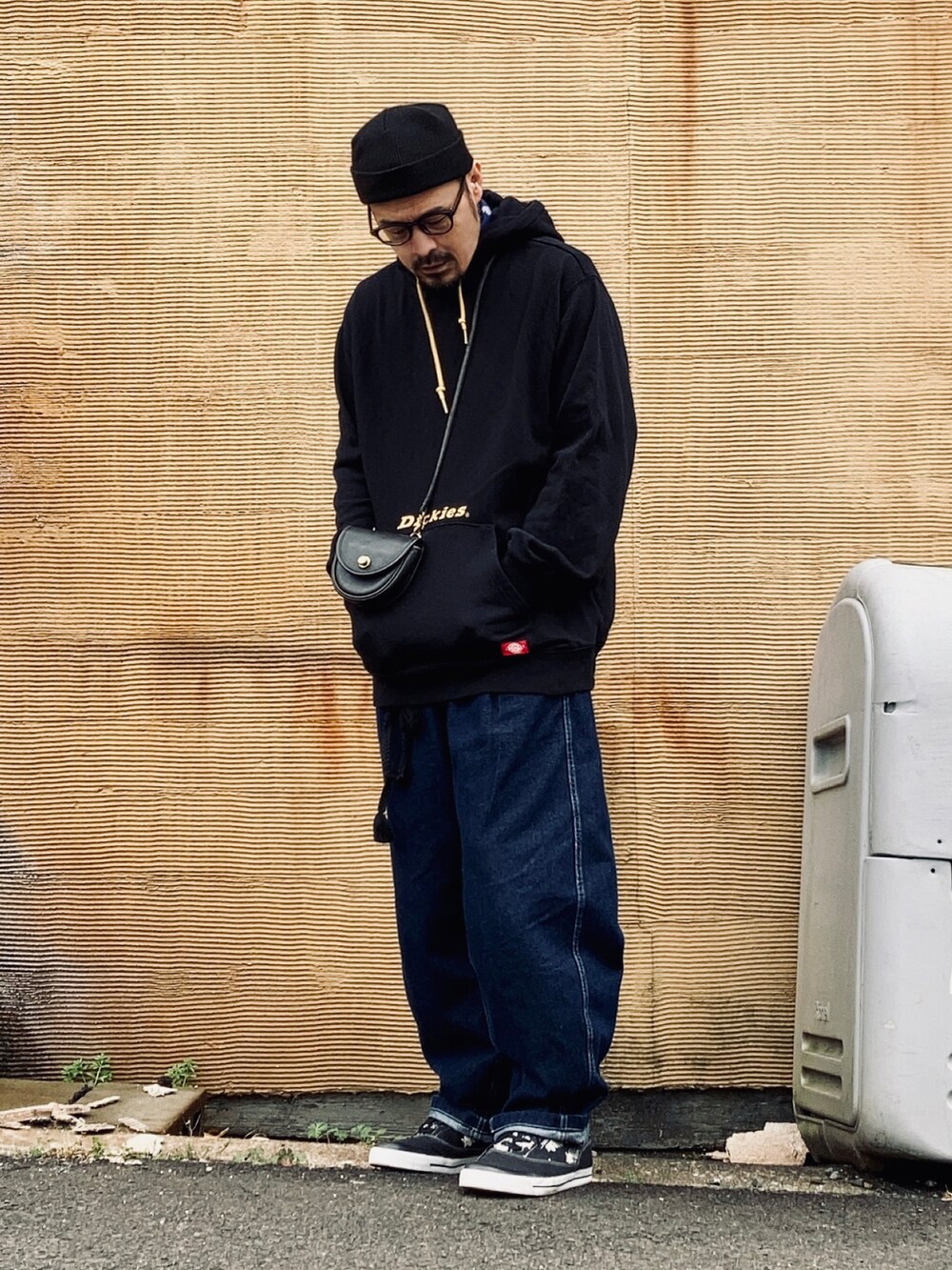 ブラック系のパーカー、ブルー系のデニムパンツ、ブラック系のスニーカーを着用したメンズの春コーディネートの2枚目の写真