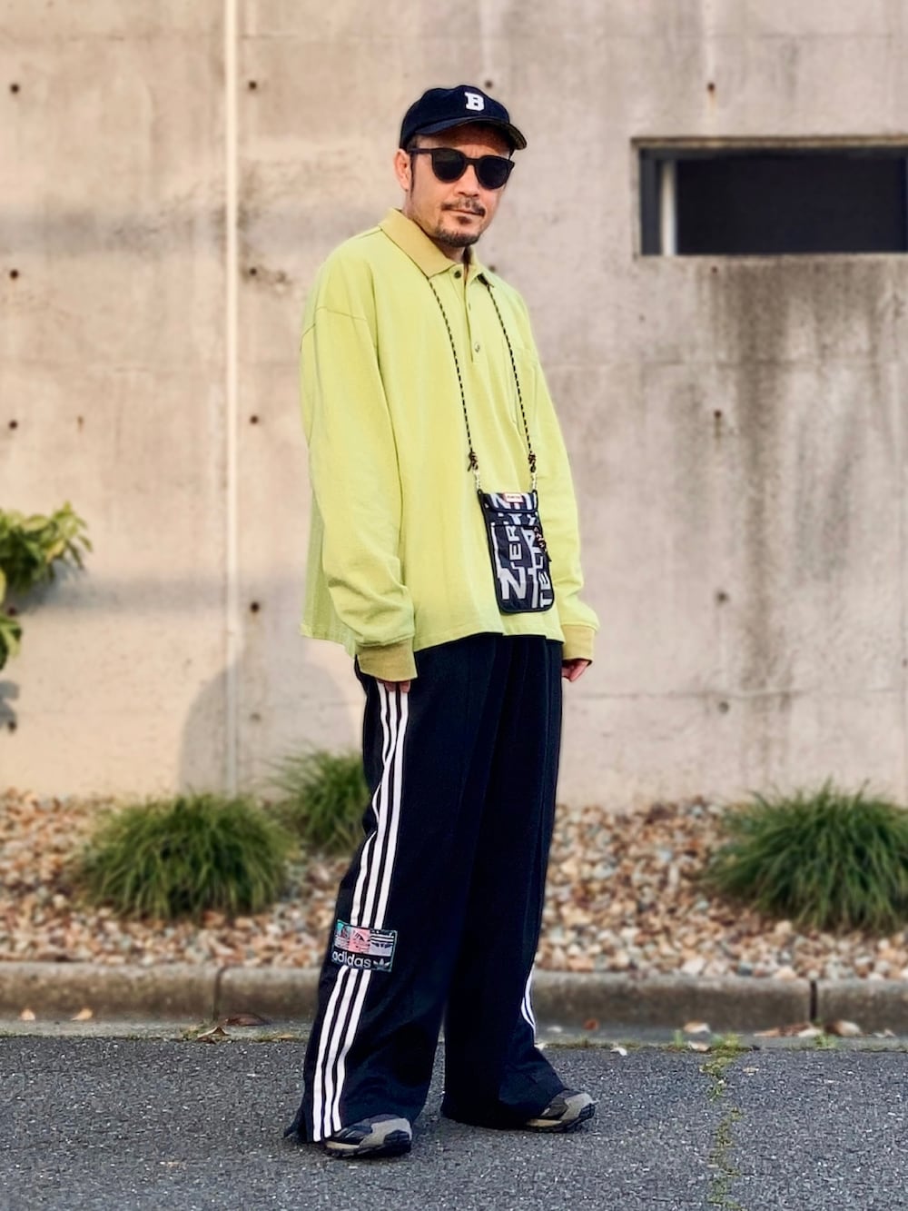 グリーン系のポロシャツ、ブラック系のスウェットパンツ、ブラック系のスニーカーを着用したメンズの春コーディネートの4枚目の写真