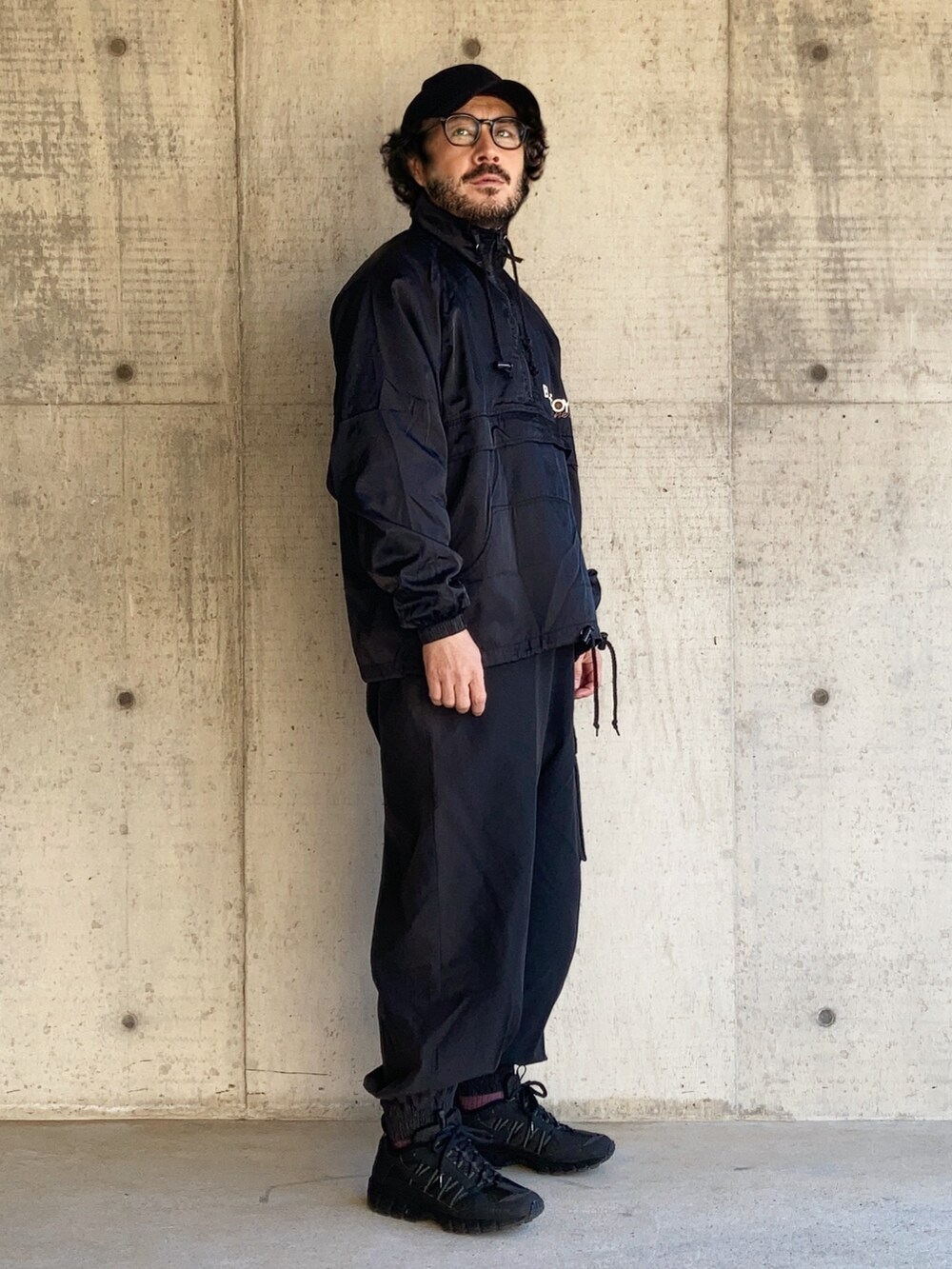 ブラック系のナイロンジャケット、ブラック系のパンツ、ブラック系のスニーカーを着用したメンズの春コーディネートの3枚目の写真