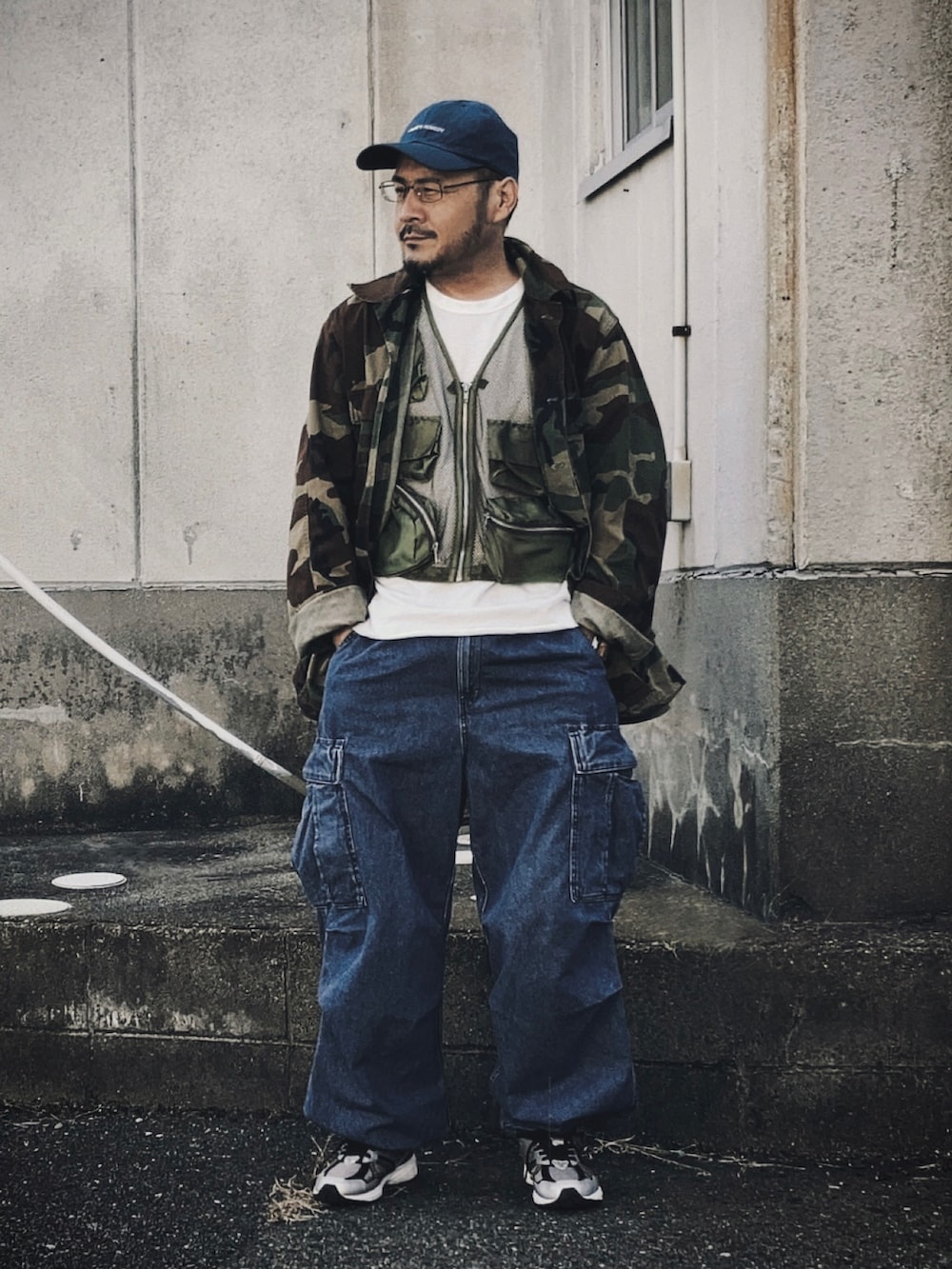 グリーン系のベスト、その他のミリタリージャケット、ブルー系のカーゴパンツを着用したメンズの秋コーディネートの2枚目の写真