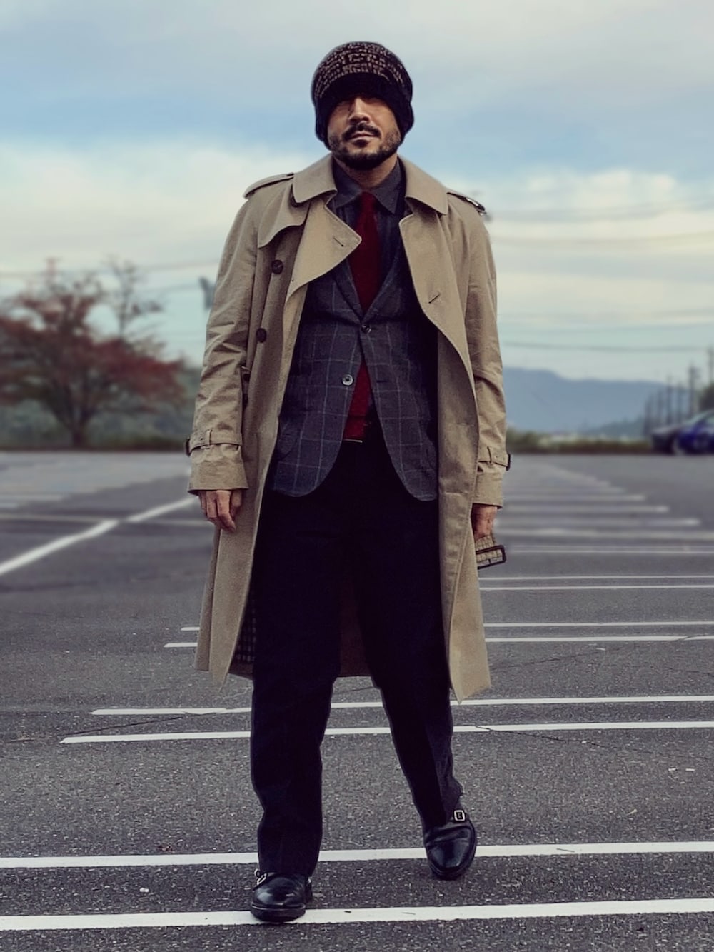 ベージュ系のトレンチコート、グレー系のテーラードジャケット、ブラック系のドレスシューズを着用したメンズの秋コーディネートの2枚目の写真