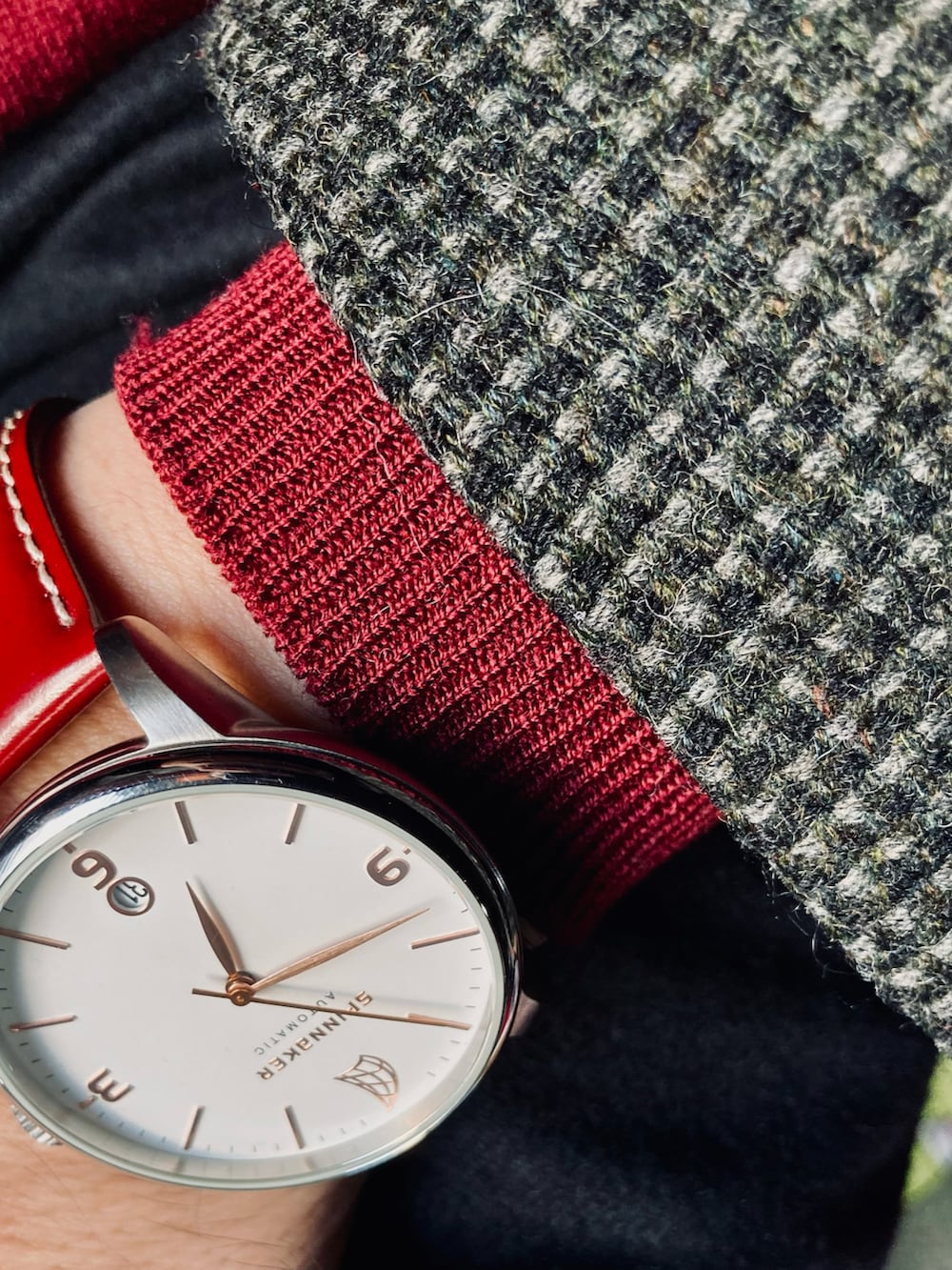 レッド系のニット/セーター、グレー系のテーラードジャケット、ブラック系のスラックスを着用したメンズの秋コーディネートの4枚目の写真