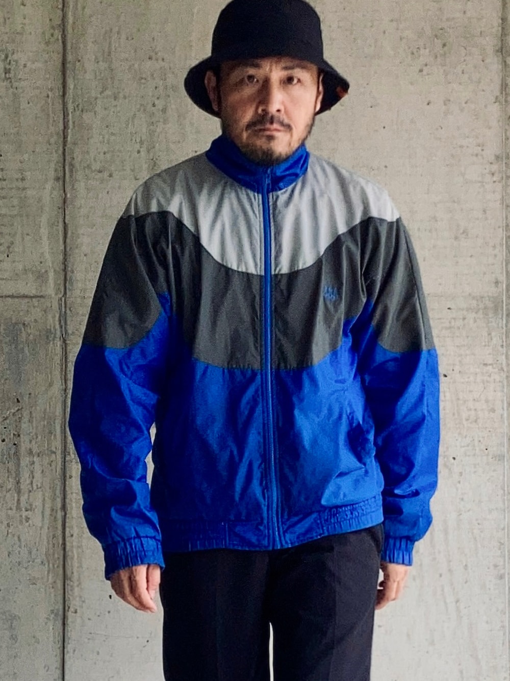 ブルー系のナイロンジャケット、ブルー系のチノパンツ、ブラック系のブーツを着用したメンズの秋コーディネートの5枚目の写真