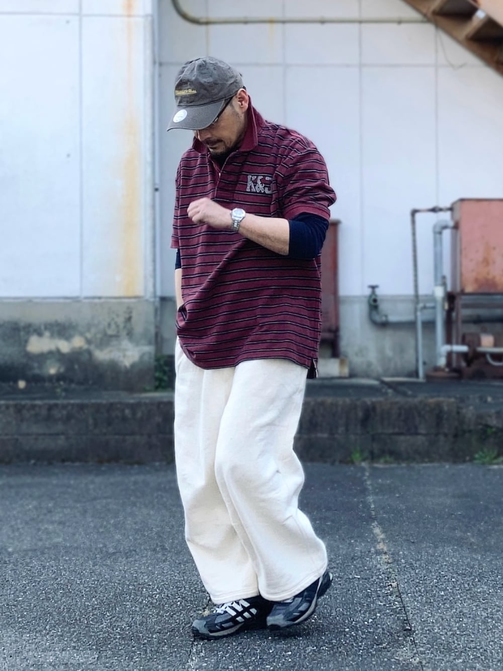 グレー系のスウェットパンツ、レッド系のポロシャツ、ブラック系のスニーカーを着用したメンズの春コーディネートの2枚目の写真