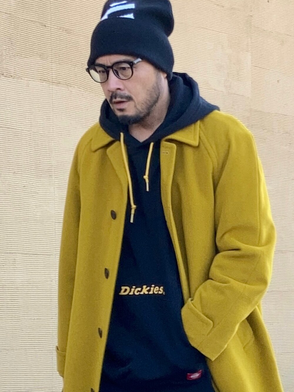 ブラック系のパーカー、イエロー系のステンカラーコート、ブラック系のその他パンツを着用したメンズの冬コーディネートの3枚目の写真