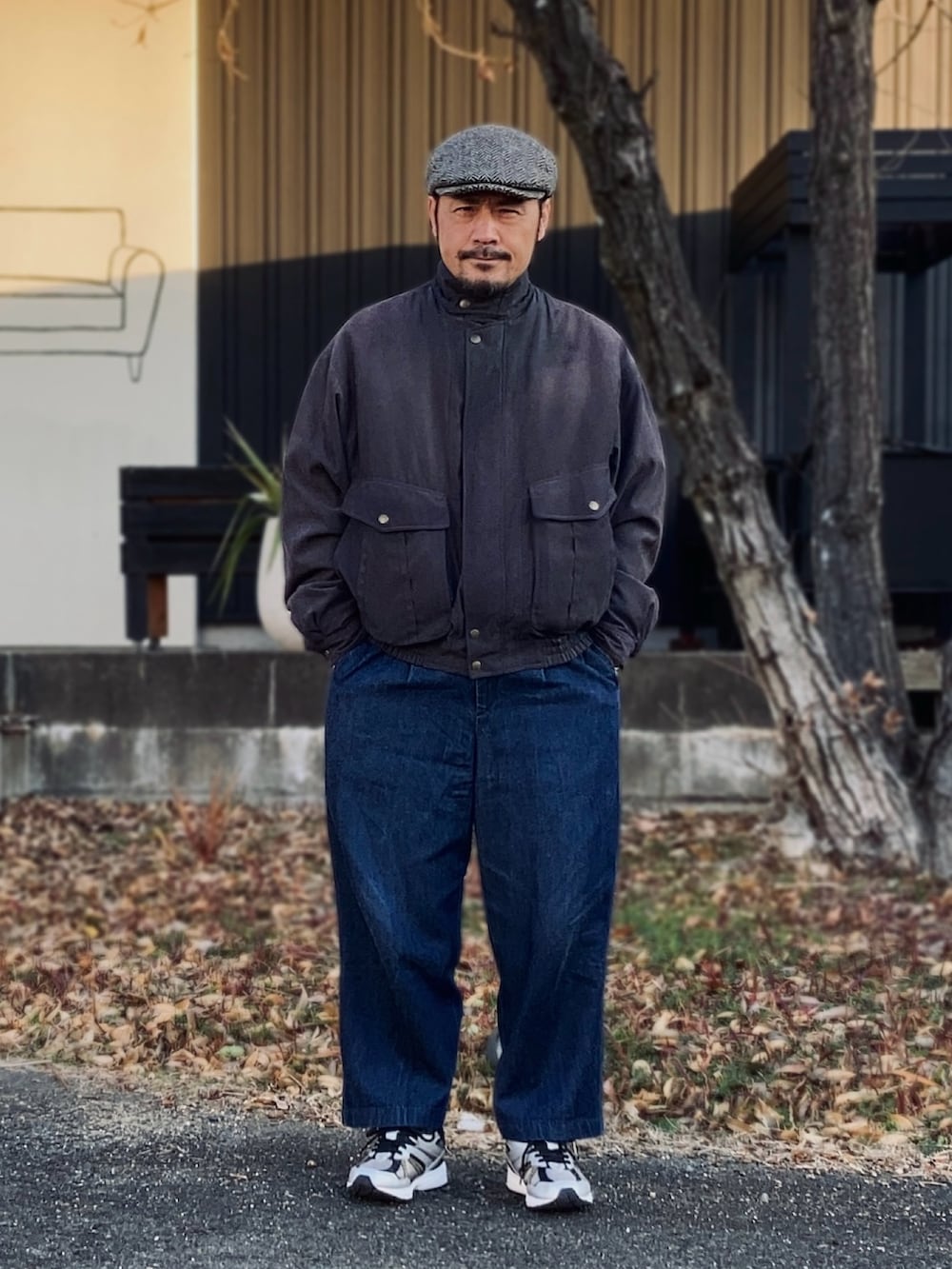 グレー系のブルゾン、ブラック系のスニーカー、ブルー系のスラックスを着用したメンズの冬コーディネートの2枚目の写真