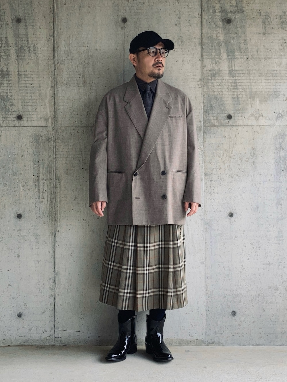 グレー系のスカート、ブラウン系のテーラードジャケット、ブラック系のブーツを着用したメンズの冬コーディネートの3枚目の写真