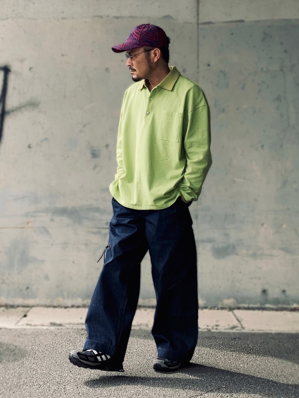 グリーン系のポロシャツ、ブルー系のデニムパンツ、ブラック系のスニーカーを着用したメンズの春コーディネートの3枚目の写真