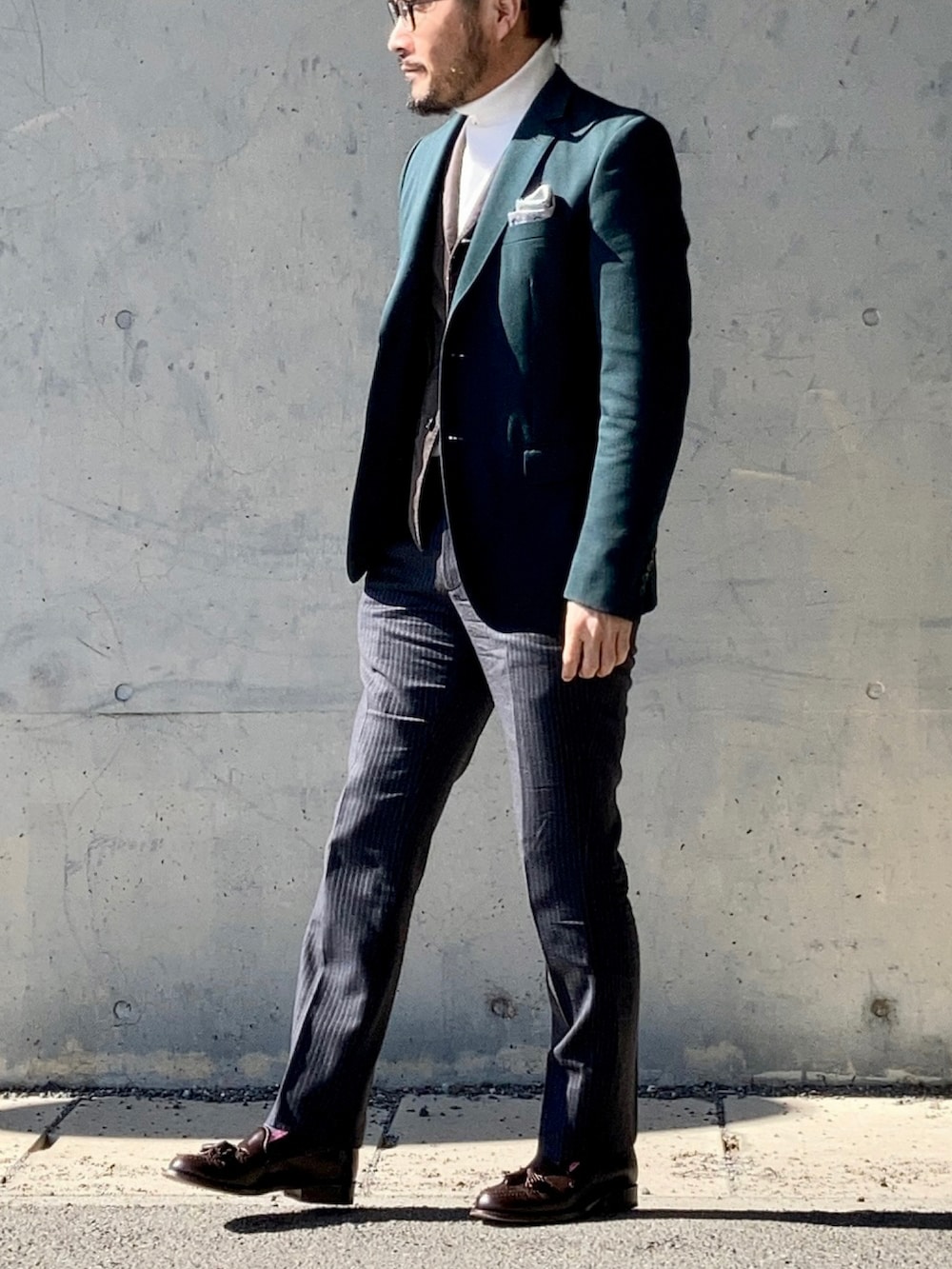 ホワイト系のニット/セーター、グリーン系のテーラードジャケット、グレー系のスラックスを着用したメンズの冬コーディネートの3枚目の写真