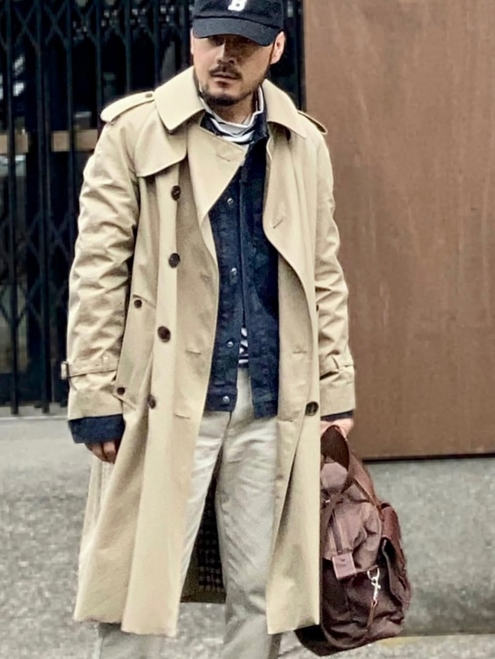 ブラック系のTシャツ/カットソー、ブルー系のデニムジャケット、ベージュ系のトレンチコートを着用したメンズの春コーディネートの2枚目の写真