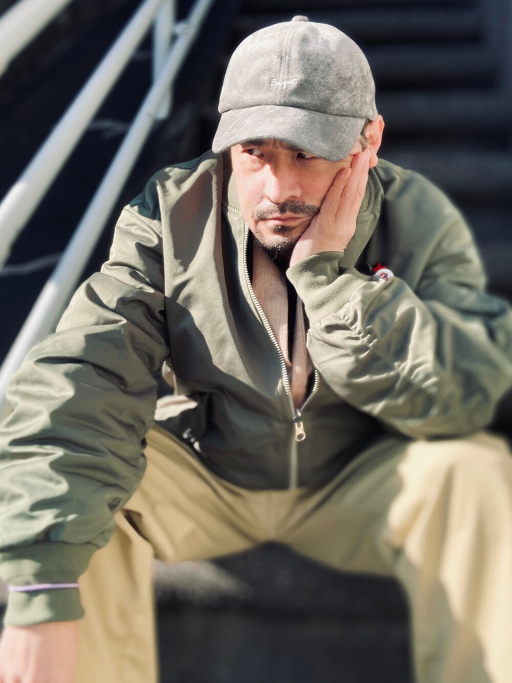 ベージュ系のTシャツ/カットソー、パープル系のスウェット、グリーン系のMA-1を着用したメンズの冬コーディネートの5枚目の写真