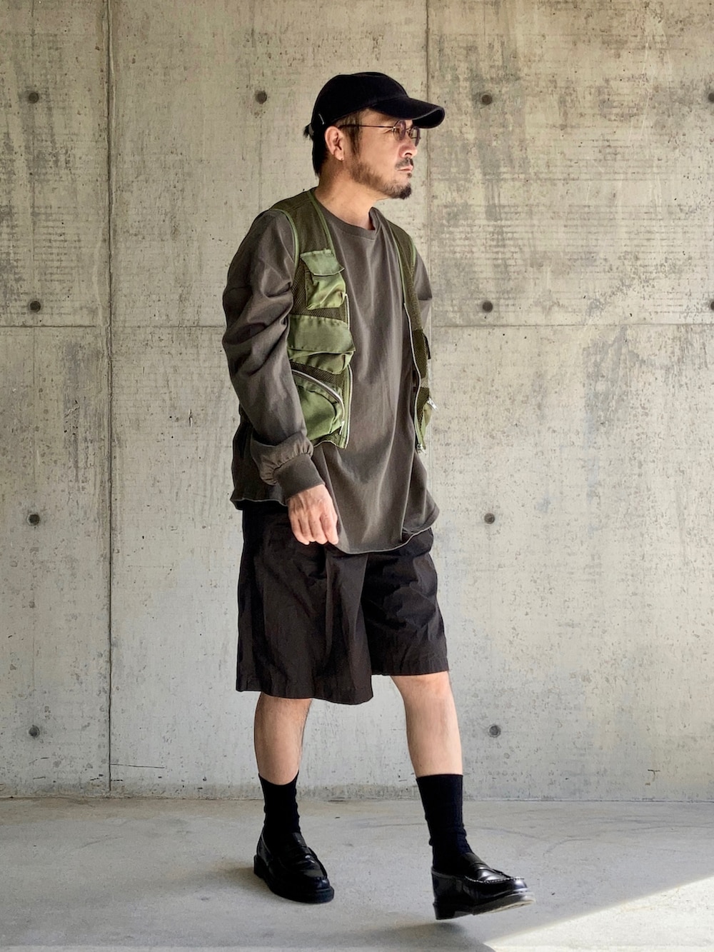 グリーン系のTシャツ/カットソー、グリーン系のベスト、ブラウン系のパンツを着用したメンズの秋コーディネートの4枚目の写真