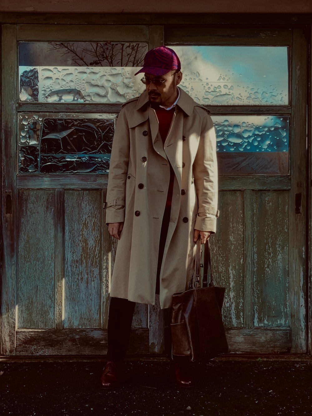 レッド系のニット/セーター、ホワイト系のシャツ/ブラウス、ベージュ系のトレンチコートを着用したメンズの秋コーディネートの5枚目の写真