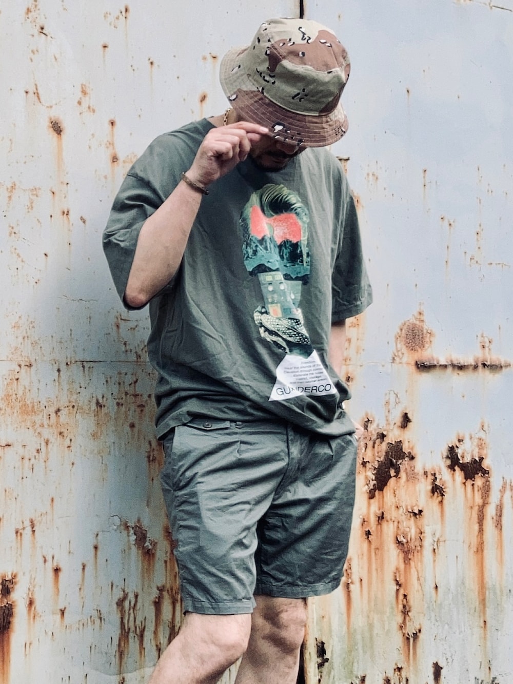 グリーン系のTシャツ/カットソー、グリーン系のチノパンツ、ブラック系のサンダルを着用したメンズの夏コーディネートの3枚目の写真