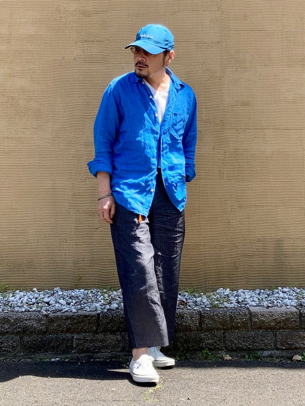 ホワイト系のTシャツ/カットソー、ブルー系のシャツ/ブラウス、グレー系のスラックスを着用したメンズの春コーディネートの4枚目の写真