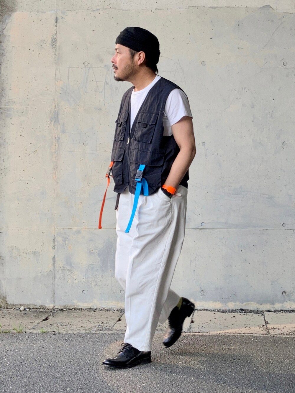 ブラック系のTシャツ/カットソー、ブラック系のベスト、ホワイト系のスラックスを着用したメンズの春コーディネートの2枚目の写真