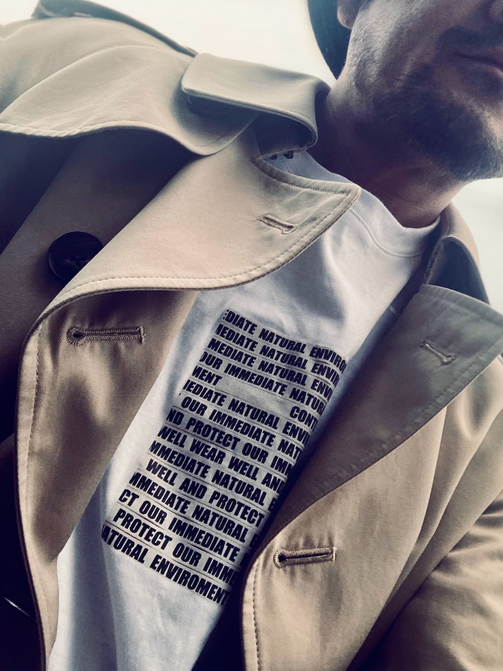 ホワイト系のTシャツ/カットソー、ベージュ系のトレンチコート、ブルー系のデニムパンツを着用したメンズの春コーディネートの4枚目の写真