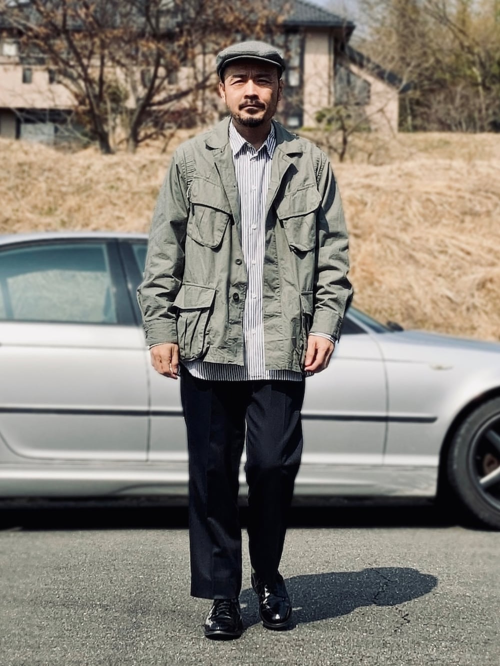 ブルー系のシャツ/ブラウス、グリーン系のミリタリージャケット、ブルー系のスラックスを着用したメンズの春コーディネートの2枚目の写真