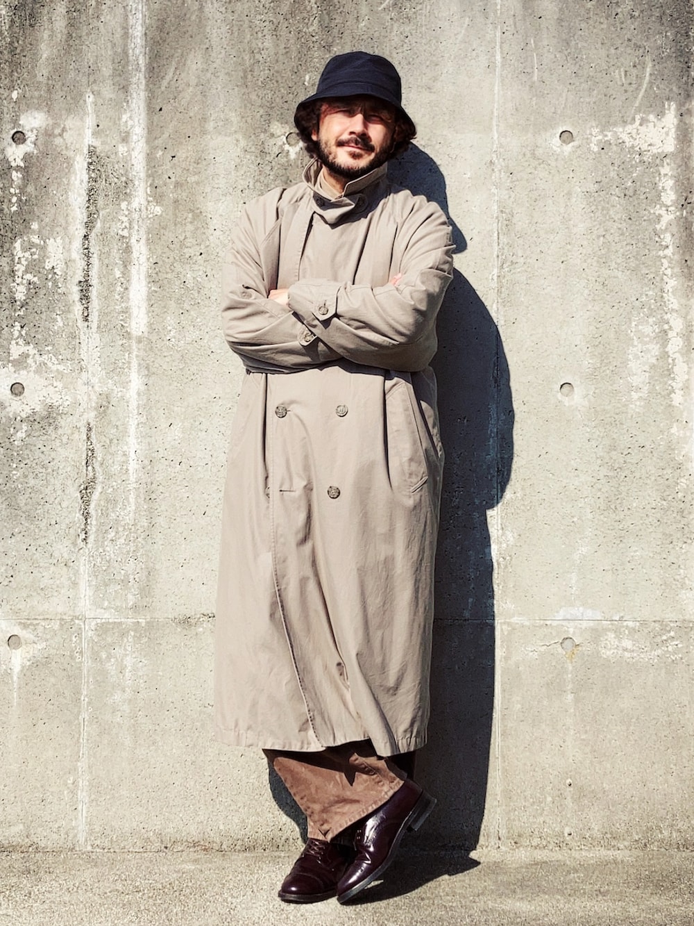 ベージュ系のトレンチコート、レッド系のニット/セーター、ブラウン系のデニムパンツを着用したメンズの冬コーディネートの3枚目の写真