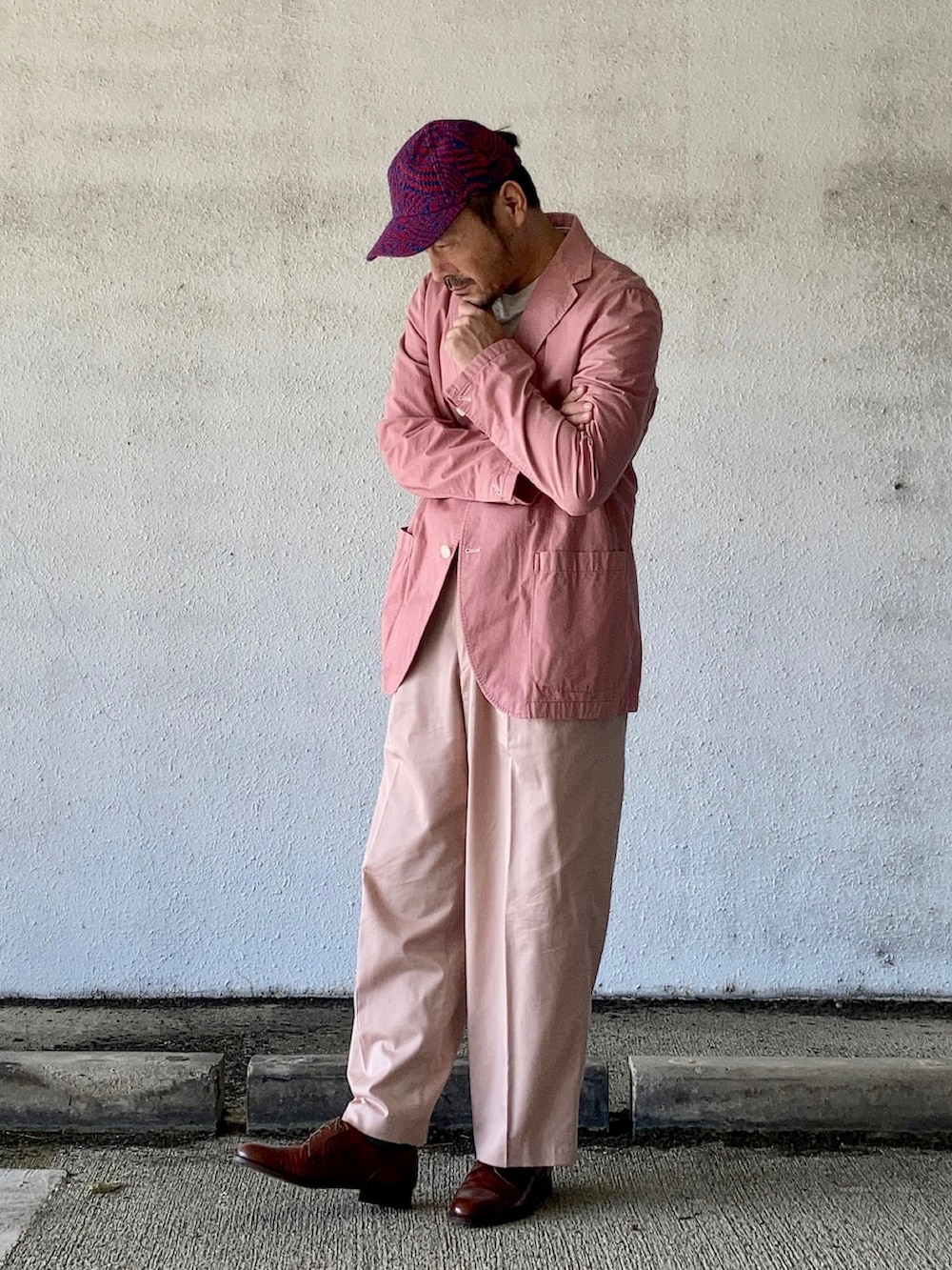 グレー系のTシャツ/カットソー、ピンク系のテーラードジャケット、ピンク系のスラックスを着用したメンズの秋コーディネートの4枚目の写真
