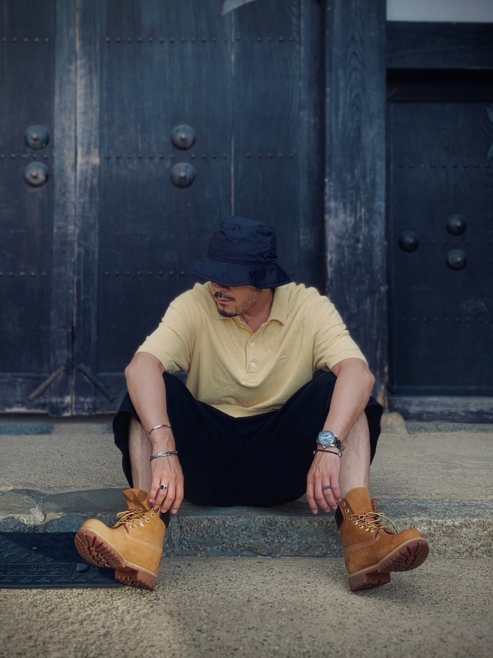 イエロー系のポロシャツ、ブラック系のその他パンツ、イエロー系のブーツを着用したメンズの夏コーディネートの4枚目の写真