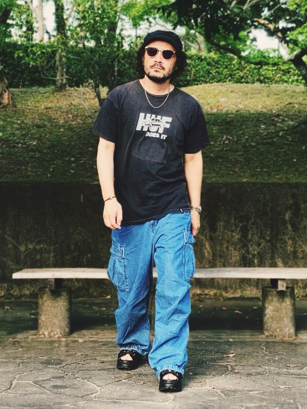 ブラック系のTシャツ/カットソー、ブルー系のカーゴパンツ、ブラック系のサンダルを着用したメンズの夏コーディネートの3枚目の写真