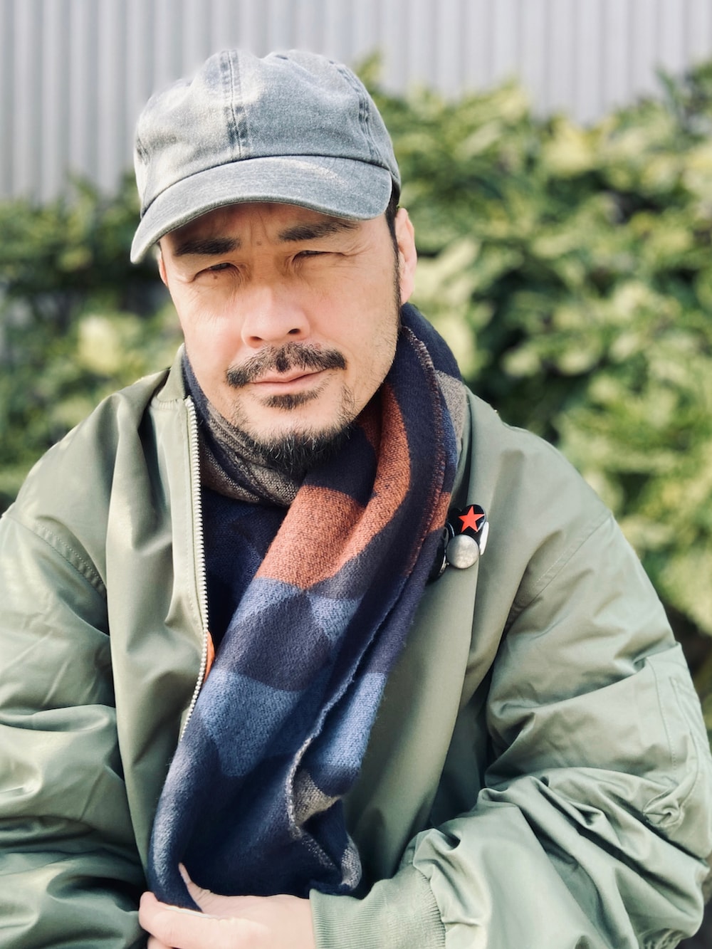 グリーン系のMA-1、グレー系のスラックス、ブラック系のドレスシューズを着用したメンズの冬コーディネートの3枚目の写真