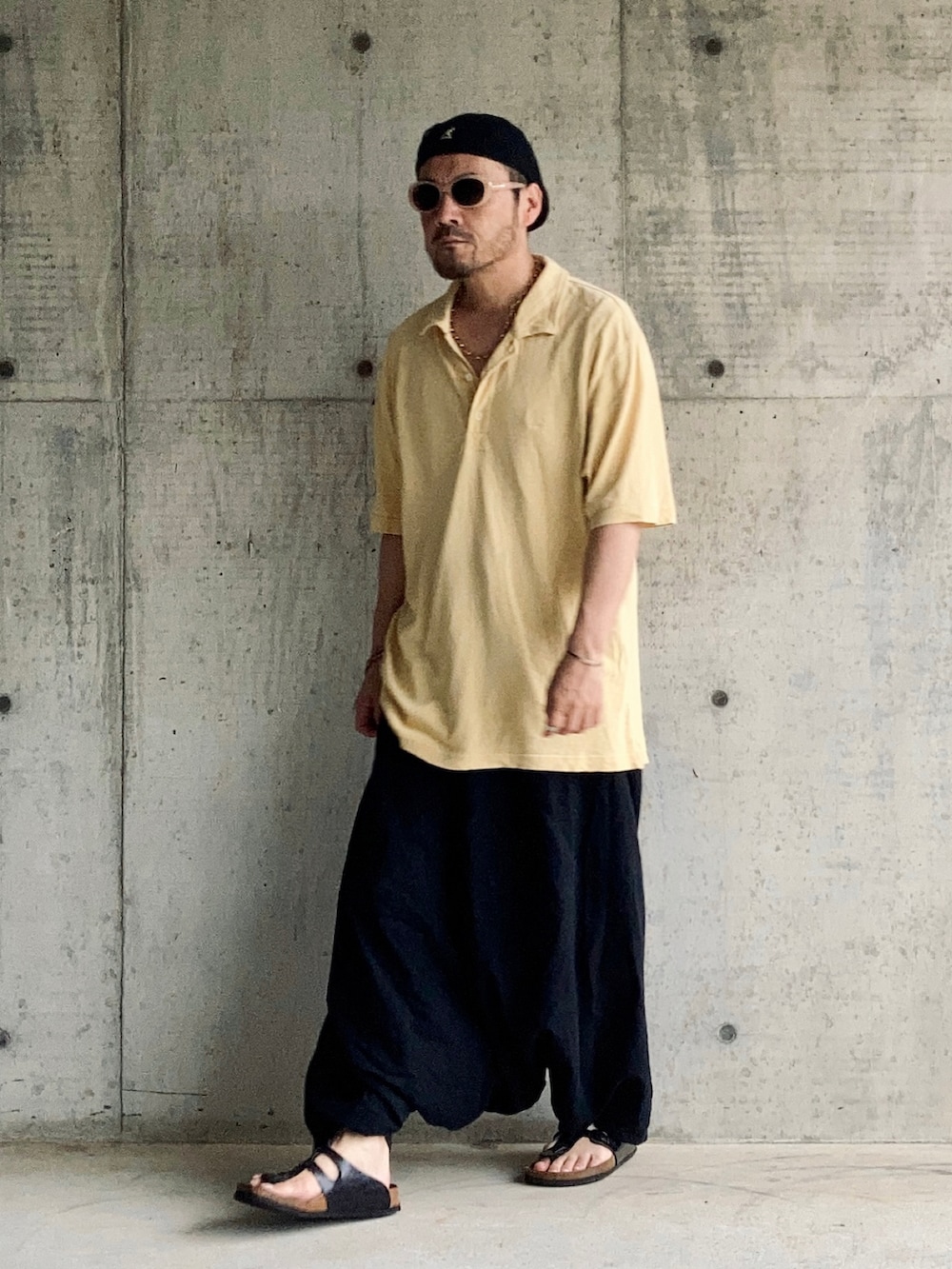 イエロー系のポロシャツ、ブラック系のその他パンツ、ブラック系のサンダルを着用したメンズの夏コーディネートの3枚目の写真