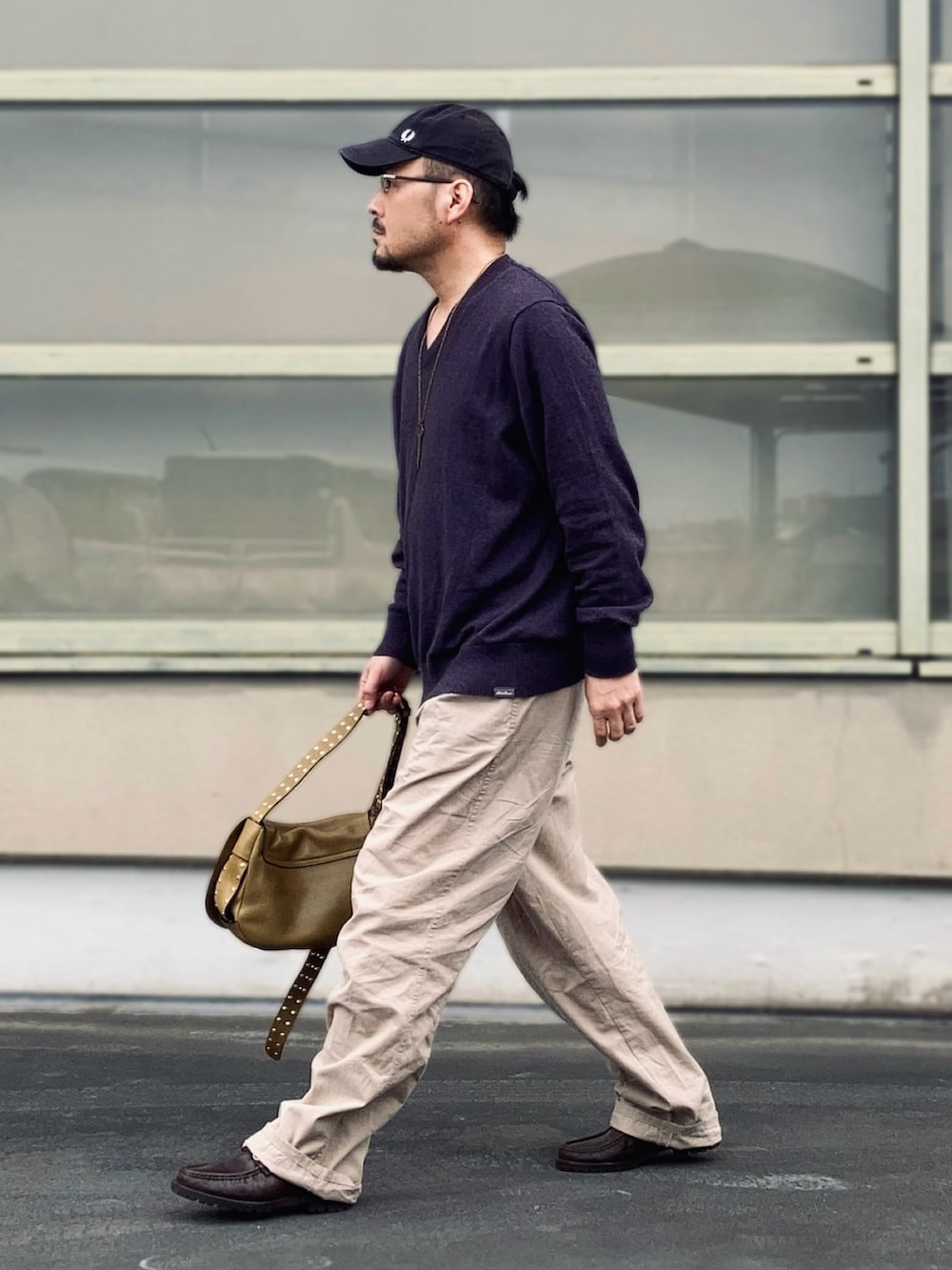 パープル系のニット/セーター、ベージュ系のスラックス、ブラウン系のブーツを着用したメンズの春コーディネートの3枚目の写真