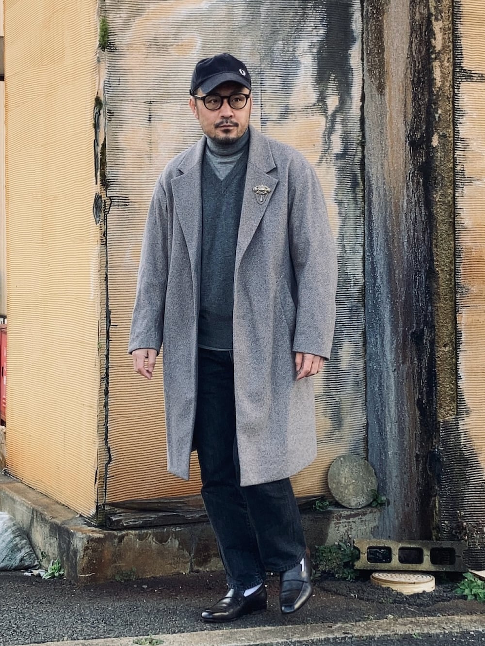 グレー系のニット/セーター、グレー系のニット/セーター、グレー系のチェスターコートを着用したメンズの冬コーディネートの2枚目の写真