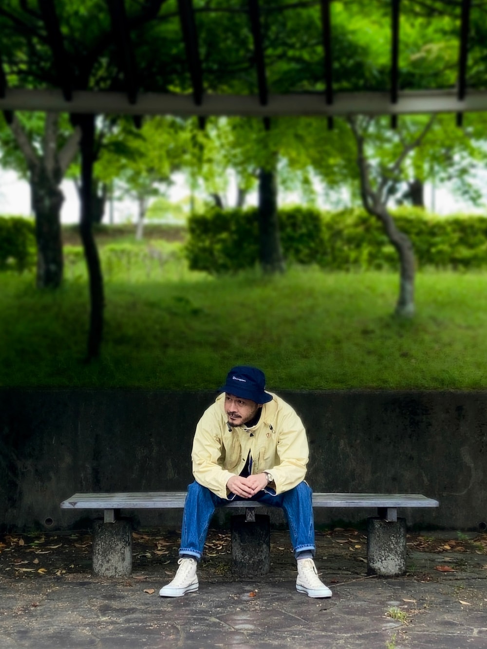 グレー系のポロシャツ、イエロー系のマウンテンパーカー、ブルー系のデニムパンツを着用したメンズの春コーディネートの2枚目の写真