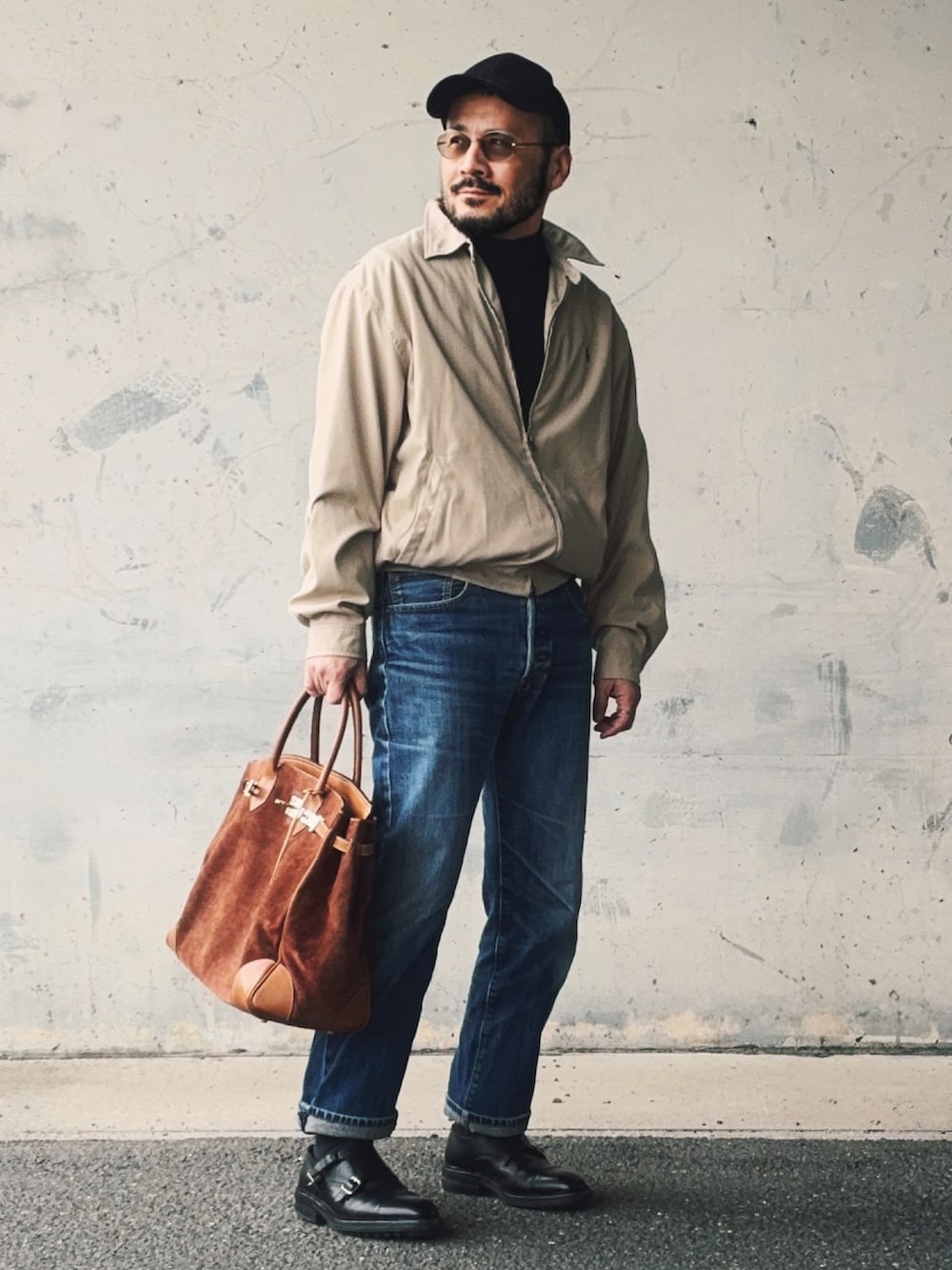 ベージュ系のブルゾン、ブルー系のデニムパンツ、ブラウン系のトートバッグを着用したメンズの冬コーディネートの2枚目の写真