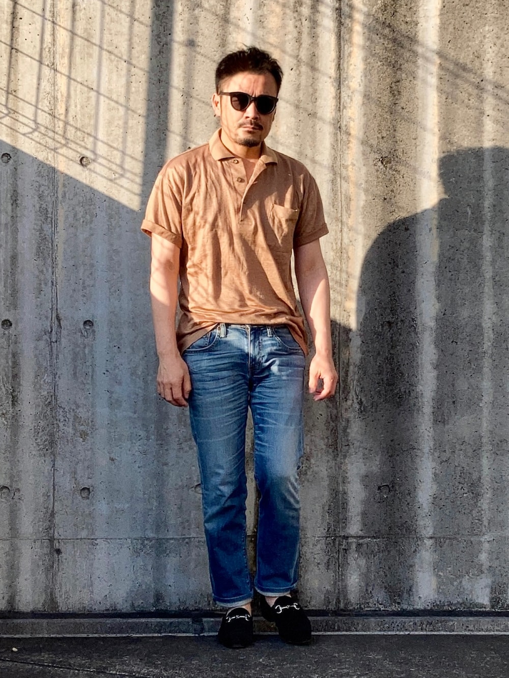 ブラウン系のポロシャツ、ブルー系のデニムパンツ、ブラック系のローファーを着用したメンズの春コーディネートの2枚目の写真