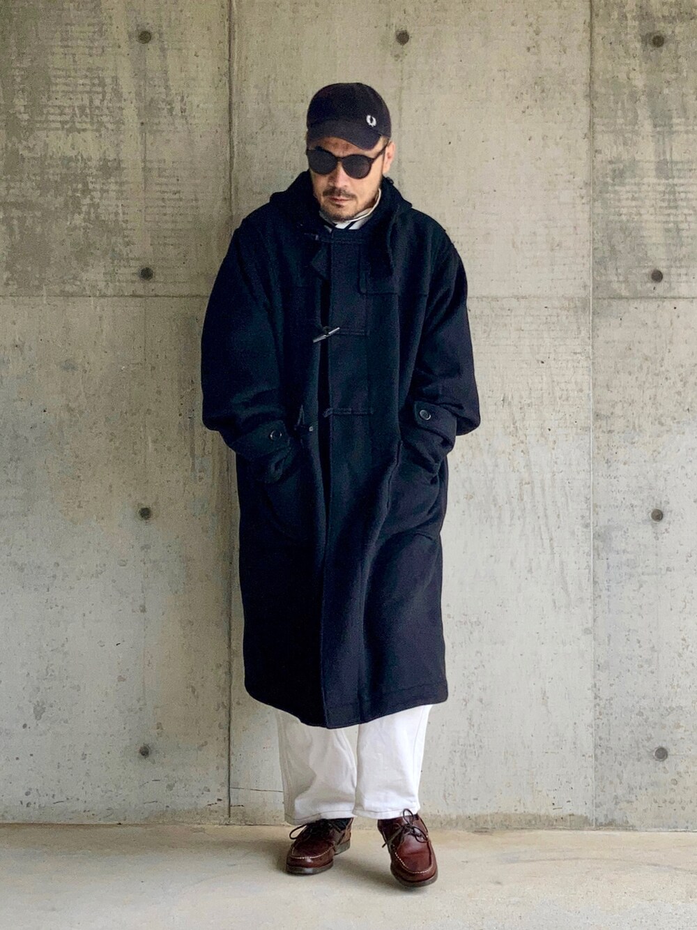 ブラック系のTシャツ/カットソー、ブラック系のダッフルコート、ホワイト系のデニムパンツを着用したメンズの秋コーディネートの4枚目の写真