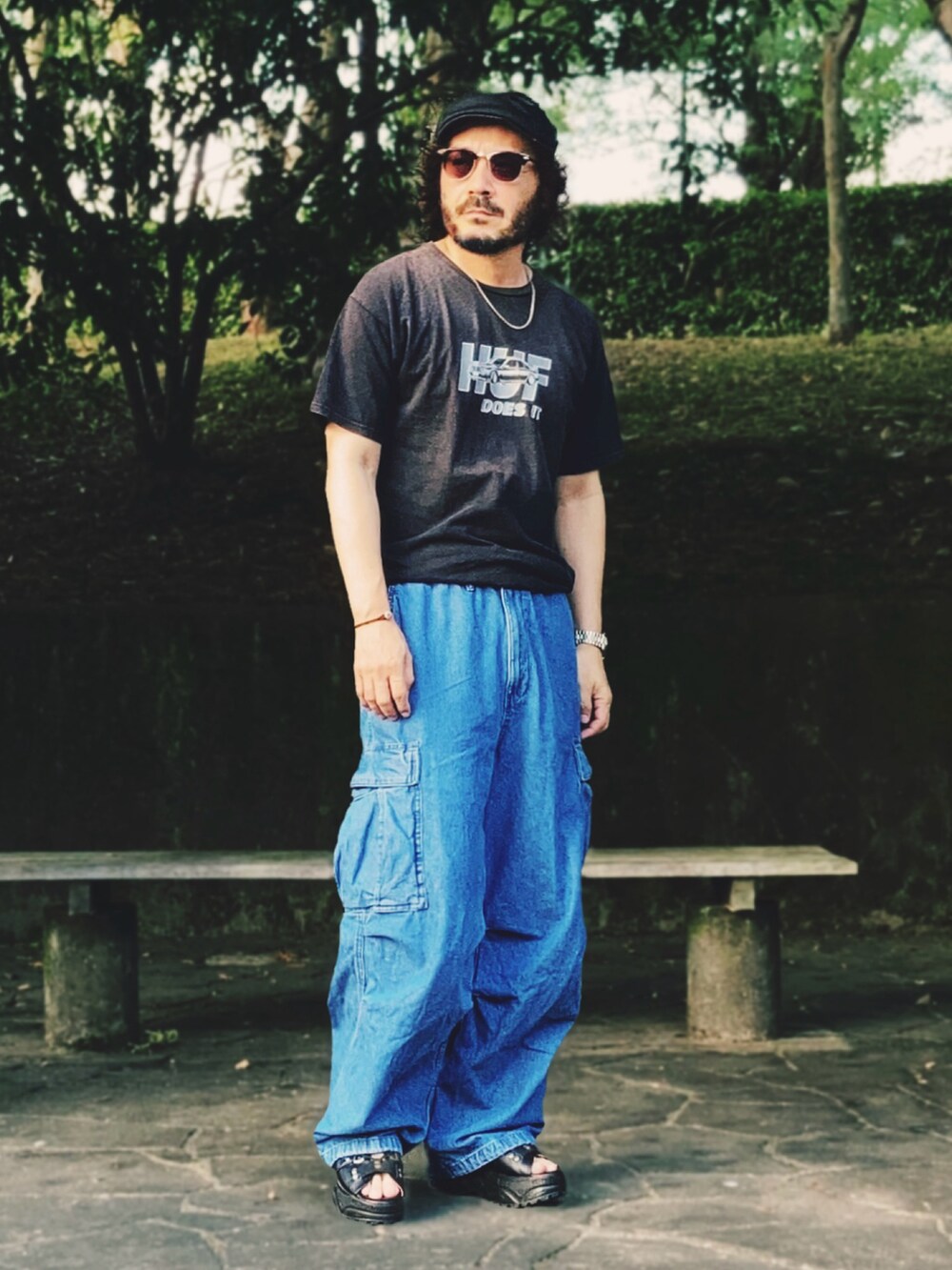 ブラック系のTシャツ/カットソー、ブルー系のカーゴパンツ、ブラック系のサンダルを着用したメンズの夏コーディネートの2枚目の写真