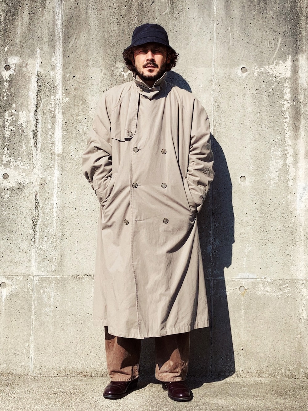 ベージュ系のトレンチコート、レッド系のニット/セーター、ブラウン系のデニムパンツを着用したメンズの冬コーディネートの4枚目の写真