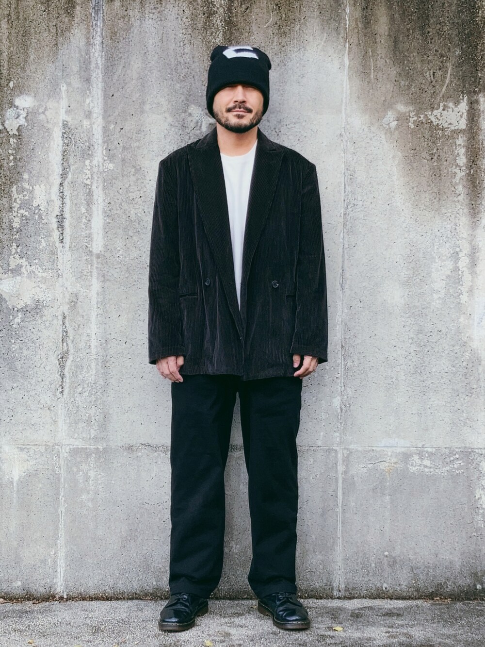 グレー系のテーラードジャケット、ブラック系のパンツ、ブラック系のブーツを着用したメンズの秋コーディネートの2枚目の写真