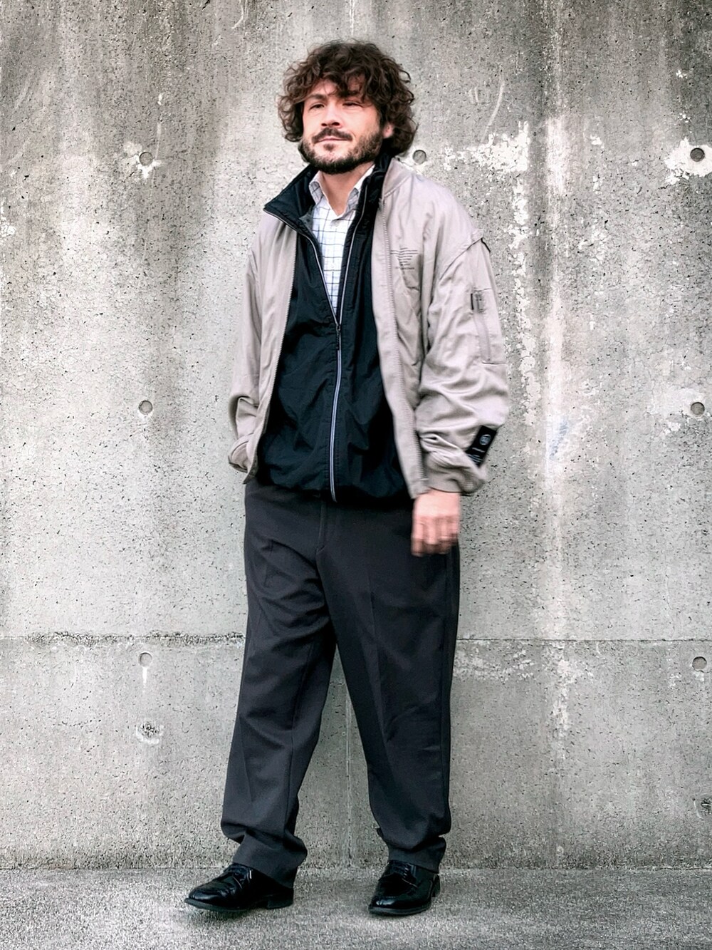 ベージュ系のMA-1、ブラック系のベスト、グレー系のスラックスを着用したメンズの冬コーディネートの3枚目の写真